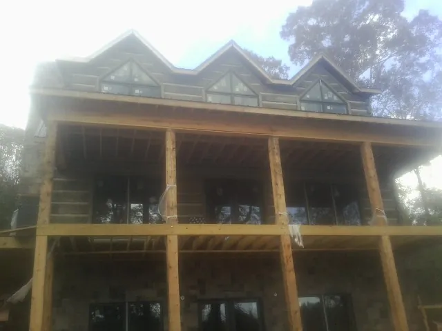 Dormers and porch framing on a large log home under construction — Roof Coating work by our crew in Fort Worth