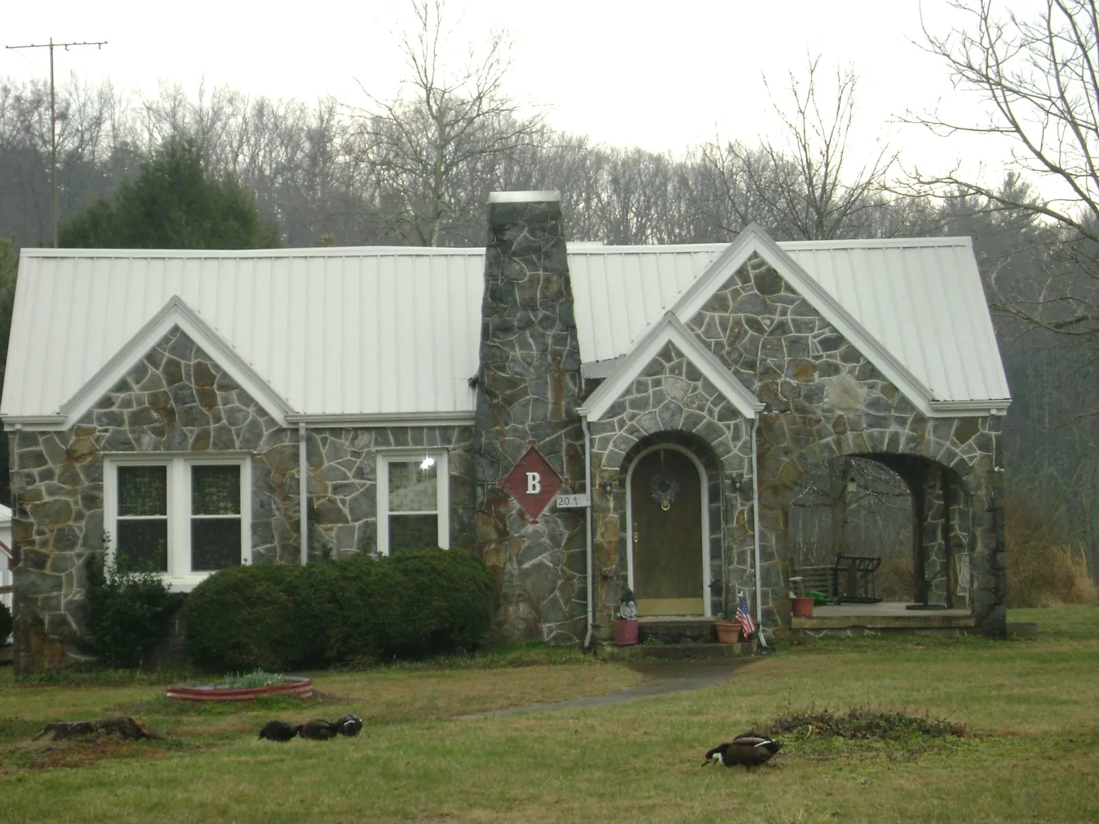 White metal roof on a stone cottage with steep gables in Fort Worth