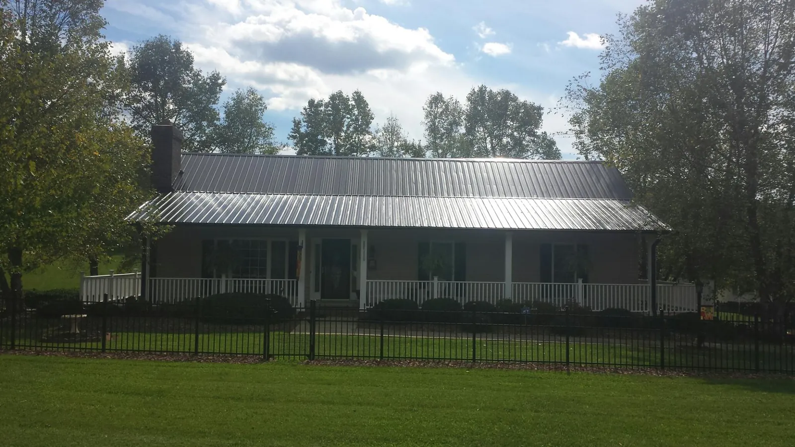 Gray metal roof on a brick ranch with a full width front porch — Gutter Guard Installation work by our crew in Fort Worth