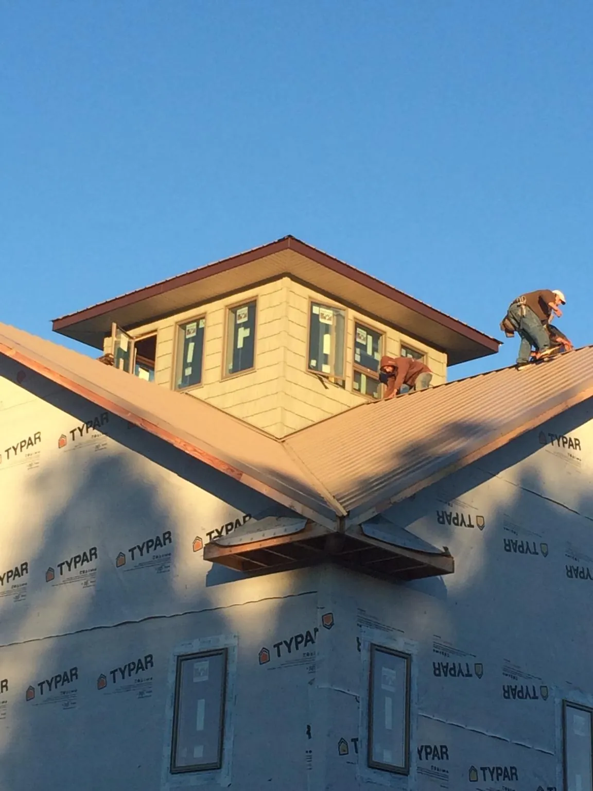 Roofers working around a rooftop cupola on a new metal roof at sunset — Roof Waterproofing in Fort Worth by Roofing Brothers
